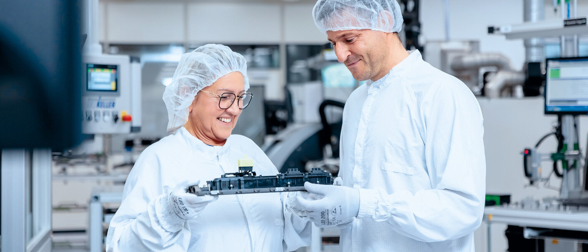 Zwei Mitarbeiter in der Produktion schauen glücklich auf ein Produkt, welches sie gemeinsam halten 