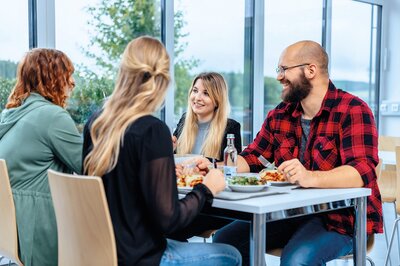 Vier Mitarbeiter beim Mittagessen in der Kantine 