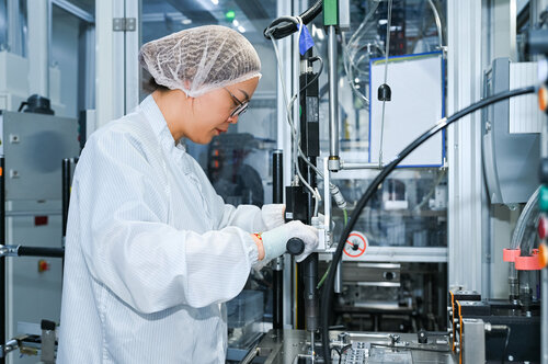 Mitarbeiterin mit Haarnetz arbeitet an einer modernen Maschine