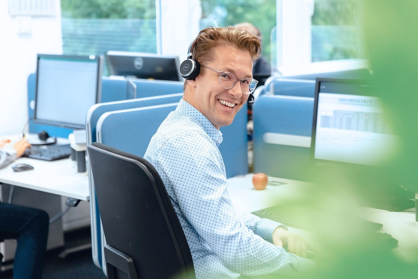 Mitarbeiter im Büro mit Headset unterstützt Kunden im After-Sales-Service für umfassende Betreuung.