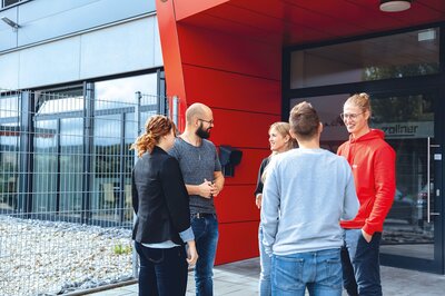 Mitarbeiter stehen vor dem Bürogebäude und unterhalten sich