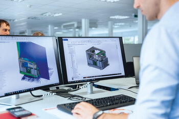 Mitarbeiter arbeitet an CAD-Modellen und mechanischen Simulationen am Computer.