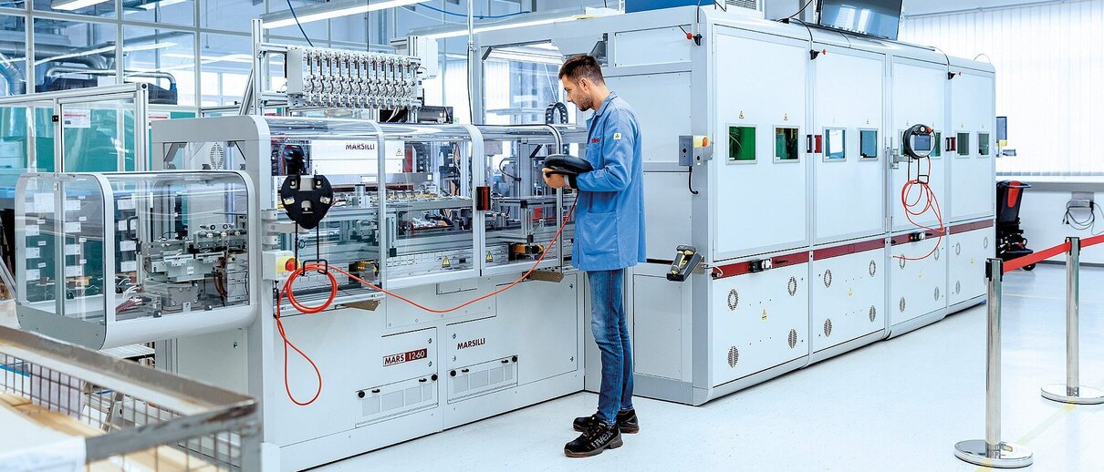 Mitarbeiter der Zollner Elektronik AG bedient eine automatisierte Produktionsanlage in einer modernen Fertigungshalle.