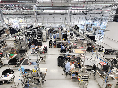 Mehrere Mitarbeiter in der Produktionshalle am arbeiten oder besprechen 
