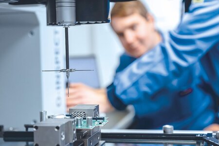 Mitarbeiter führt hochpräzise geometrische Messung an Bauteil mit berührungsloser Messtechnik durch.