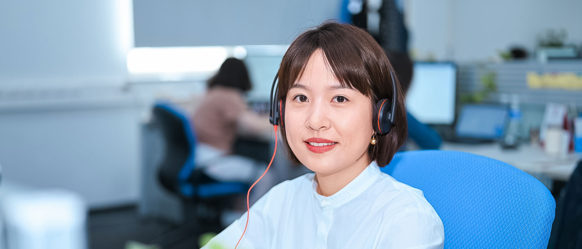 Mitarbeiterin der Zollner Elektronik AG mit Headset arbeitet im Bürobereich am Computer im Rahmen des Supply-Chain-Managements.