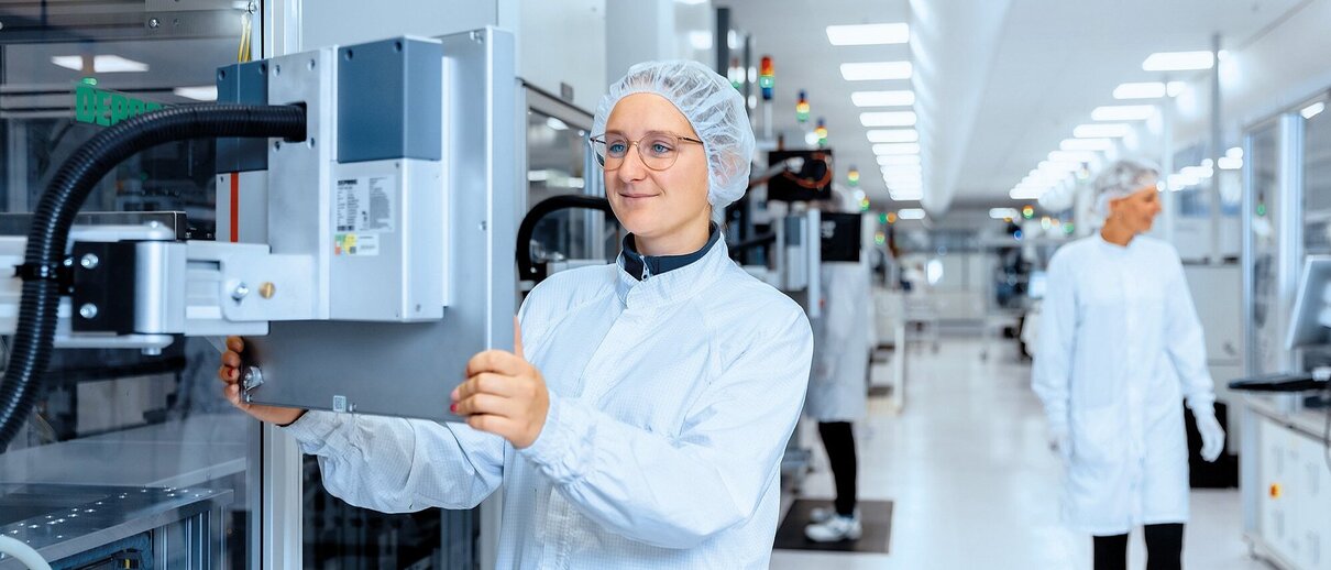 Mitarbeiterin der Zollner Elektronik AG in Reinraumkleidung bedient Fertigungsanlage