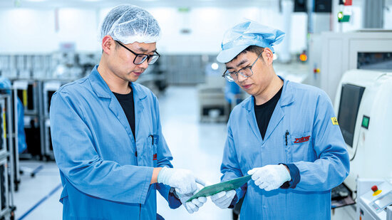 Zwei Mitarbeiter aus der Produktion, sehen sich eine Leiterplatte an 