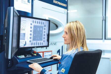 Mitarbeiterin bedient Röntgenmikroskop zur zerstörungsfreien Prüfung von Leiterplatten und Baugruppen mit CT-Analyse und 3D-Modellierung.