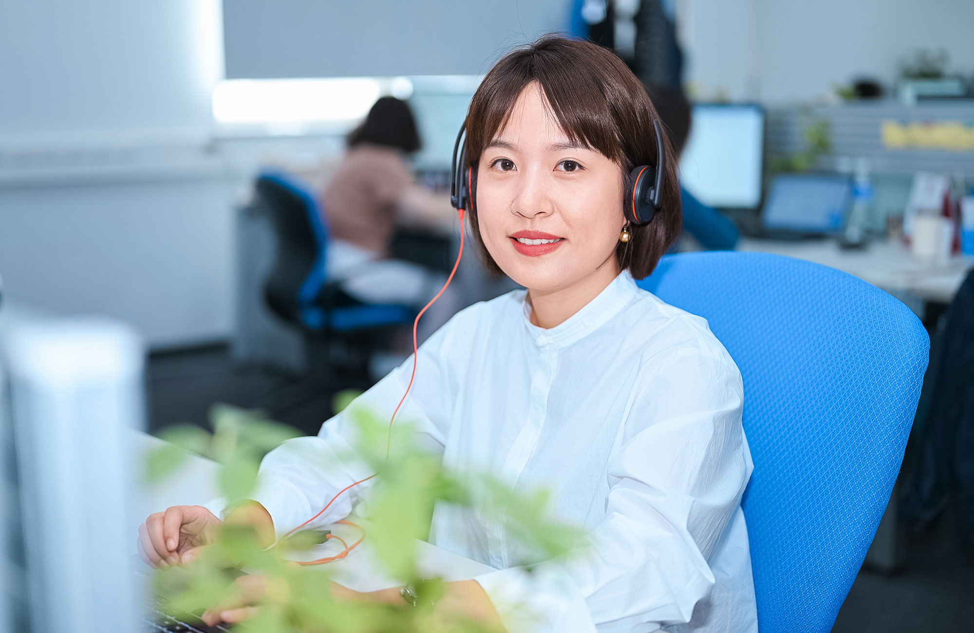 Mitarbeiterin der Zollner Elektronik AG mit Headset arbeitet im Bürobereich am Computer im Rahmen des Supply-Chain-Managements.